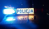 fotografia kolorowa przedstawiająca radiowóz policyjny w porze nocnej z włączoną sygnalizacją świetlną