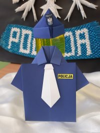 Fotografia przedstawiająca koszulę policyjną zrobioną z origami krawat i furażerkę