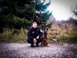 Fotografia kolorowa przedstawiająca policjanta wraz z psem