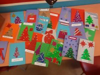 Fotografia kolorowa przedstawiająca kartki świąteczne leżące na stoliku w klasie.