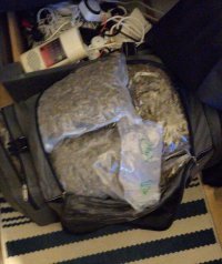 Fotografia kolorowa przedstawiająca marihuanę zapakowaną w worki foliowe ułożone w torbie podróżnej