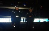 Fotografia kolorowa przedstawiająca policjantów stojących przy radiowozie w porze nocnej