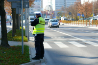 fotografia kolorowa przedstawiająca policjanta wykonującego ręczny pomiar prędkości