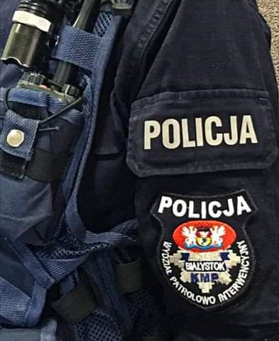 Ramię policjanta, na ramieniu naszywka z napisem Wydział Patrolowo-Interwencyjny w Białymstoku a nad nim napis Policja