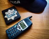 policyjna czapka, odznaka  i telefon leżące na stole