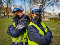 Umundurowany Policjant ruchu drogowego oraz policjantka w maseczkach zakrywających usta i nos
