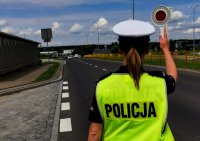 Policjantka nadająca tarczą do zatrzymania sygnał dla kierowcy
