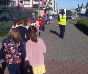 Dzieci idące chodnikiem z policjantką