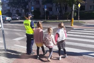 Policjantka przechodząca przez przejście z trójką dzieci