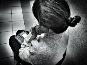 kobieta siedząca na krześle, która trzyma w dłoni słuchawkę telefonu