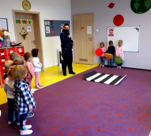 Na środku stojąca policjantka, po bokach sali przedszkolaki