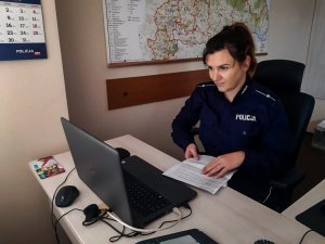 Policjantka siedząca przy biurku, przed nią rozłożony laptop. Policjantka przeprowadza wirtualną lekcję