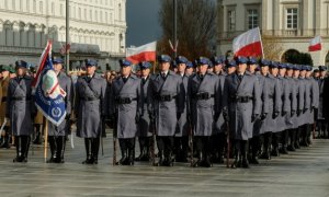 Policjanci ustawieni w szeregach, w tle flagi Polski