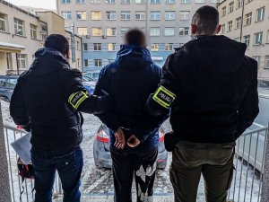 policjanci w cywilnych ubraniach, którzy trzymają zatrzymanego mężczyznę