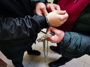 policjant zakłada zatrzymanemu kajdanki zespolone na ręce