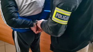 policjant w ubraniach cywilnych zakłada kajdanki na ręce trzymane z tyłu