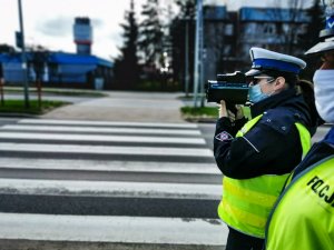 policjantka ruchu drogowego, która stoi w rejonie przejścia dla pieszych i dokonuje pomiaru prędkości