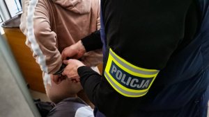 policjant kryminalny w cywilnych ubraniach zakłada kobiecie kajdanki na ręce trzymane z tyłu