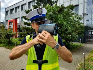 umundurowany policjant dokonuje pomiaru prędkości przy użyciu specjalnego urządzenia