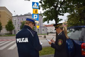 policjantka drogówki, funkcjonariuszka Straży Miejskiej oraz pracownik Zarządu Dróg Miejskich sprawdzają znaki  w rejonie szkół