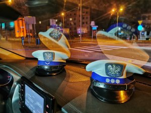 Policyjne czapki leżące na podszybiu radiowozu