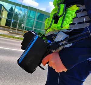 Policjant trzymający w ręku urządzenie do pomiaru prędkości