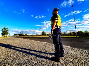 Policjant z tarczą do zatrzymań w ręku stojący przy drodze