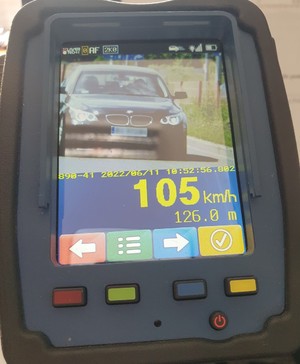 Wyświetlacz urządzenia do pomiaru prędkości pokazujący samochód i prędkość 105 kilometrów na godzinę.