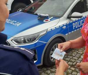 Policjantka wręcza ulotkę dziecku