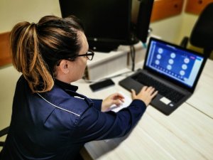 umundurowana policjantka siedząca przed laptopem, która prowadzi lekcję online