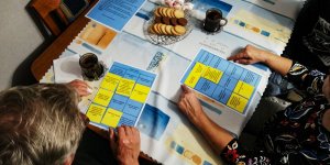 seniorzy siedzą przy stole i grają w grę bingo