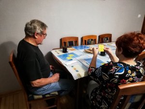 seniorzy siedzą przy stole i grają w grę bingo
