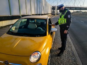 policjant z Wydziału Ruchu Drogowego podczas kontroli stanu trzeźwości kierowcy żółtetgo fiata