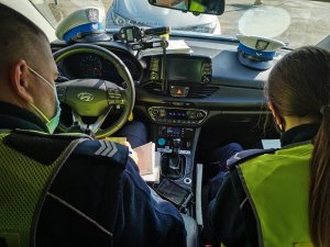 Policjanci siedzący w radiowozie wypełniający dokumentację