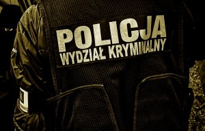 plecy policjanta z czarną kamizelką z napisem "policja"