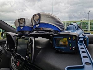 dwie policyjne czapki policjantów z ruchu drogowego oraz urządzenie do pomiaru prękości