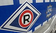 Symbol R w kółku na niebieskim tle charakterystyczny dla Wydziału Ruchu Drogowego