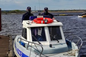 policjanci stojący na służbowej łodzi