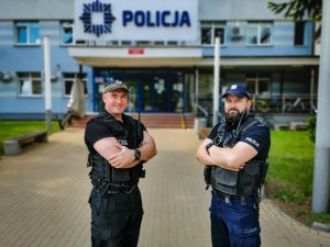 po lewej stronie funkcjonariusz Straży Miejskiej, po prawej białostocki policjant. Mundurowi stoją na tle Komendy Miejskiej Policji w Białymstoku.