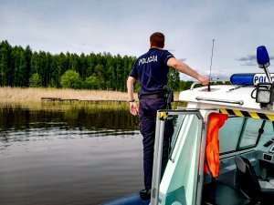 Policjant stojący na łódce obserwujący wodę
