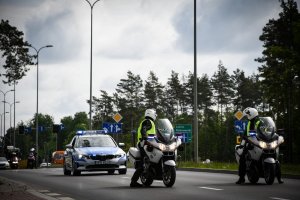 na pierwszym planie policjanci na motocyklach, a za nimi policyjny radiowóz