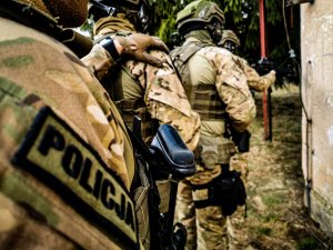 policyjni kontrterroryści podczas ćwiczeń. Mundurowi stoją przy ścianie i trzymają się za ramię