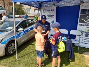 Dwójka dzieci stojąca na przeciwko policjantki