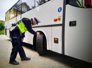 policjant z drogówki sprawdza opony autobusu