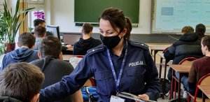 policjantka rozdaje młodzieży ulotki