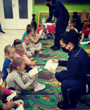 POLICJANTKI ROZDAJĄCE DZIECIOM KOLOROWANKI