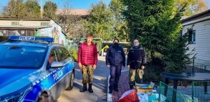 policjantka przy radiowozie, obok przekazana karma do schroniska