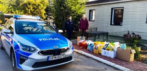 policjantka przy radiowozie, obok przekazana karma do schroniska