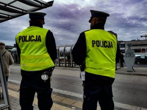 Dwóch policjantów stojących na przystanku autobusowym.