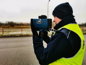 Policjant mierzący prędkość ręcznym miernikiem prędkości.